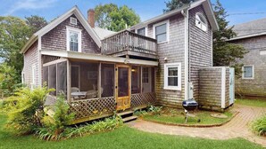 Une maison à deux étages dotée d’un porche abrité, d’une petite terrasse et d’un jardin avec un barbecue.