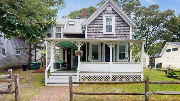 Une maison à deux étages avec un porche, une porte d’entrée et un petit jardin.