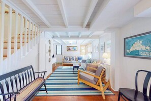 Un vaste espace de vie agrémenté d’un tapis à rayures, de meubles en bois et d’un escalier avec des rampes blanches.