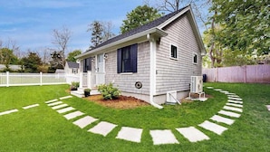 A single-story house with a front porch, a small garden, and a white picket fence. - Beautifully remodeled cottage near the beach with central AC, gas grill & lawn (Orleans)