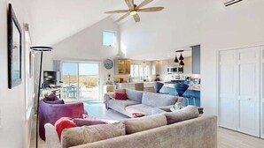 A spacious living area with a large sofa, a coffee table, and a floor lamp. - Cozy cottage steps to the beach with patio, W/D, & partial AC (North Truro)