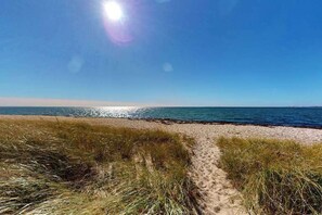 Ein Strandweg, der zum Meer führt, bei blauem Himmel.