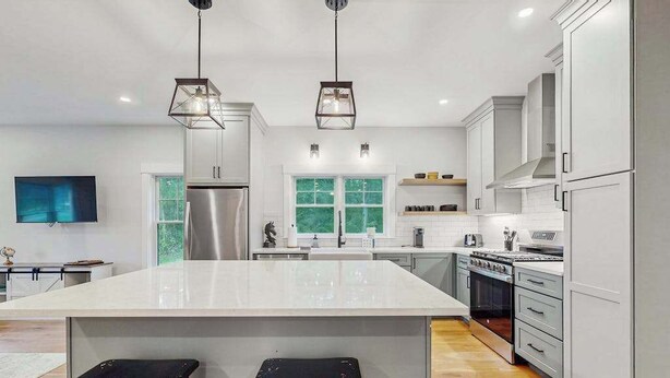Una cocina moderna con una isla grande, electrodomésticos de acero inoxidable e iluminación colgante.