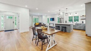 Una cocina moderna con una isla central, comedor y sala de estar con sofá y televisor.
