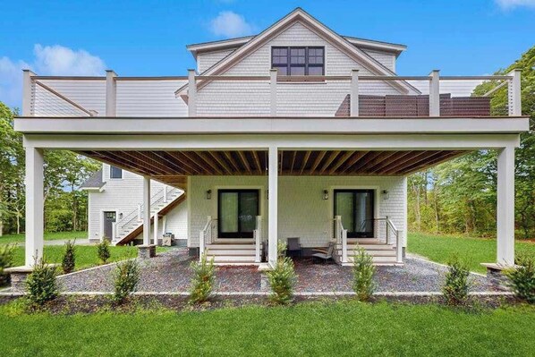 A two-story house with a covered porch, a second-level balcony, and a landscaped front yard.