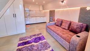 A modern living room with a sofa, a patterned rug, and a kitchen in the background.