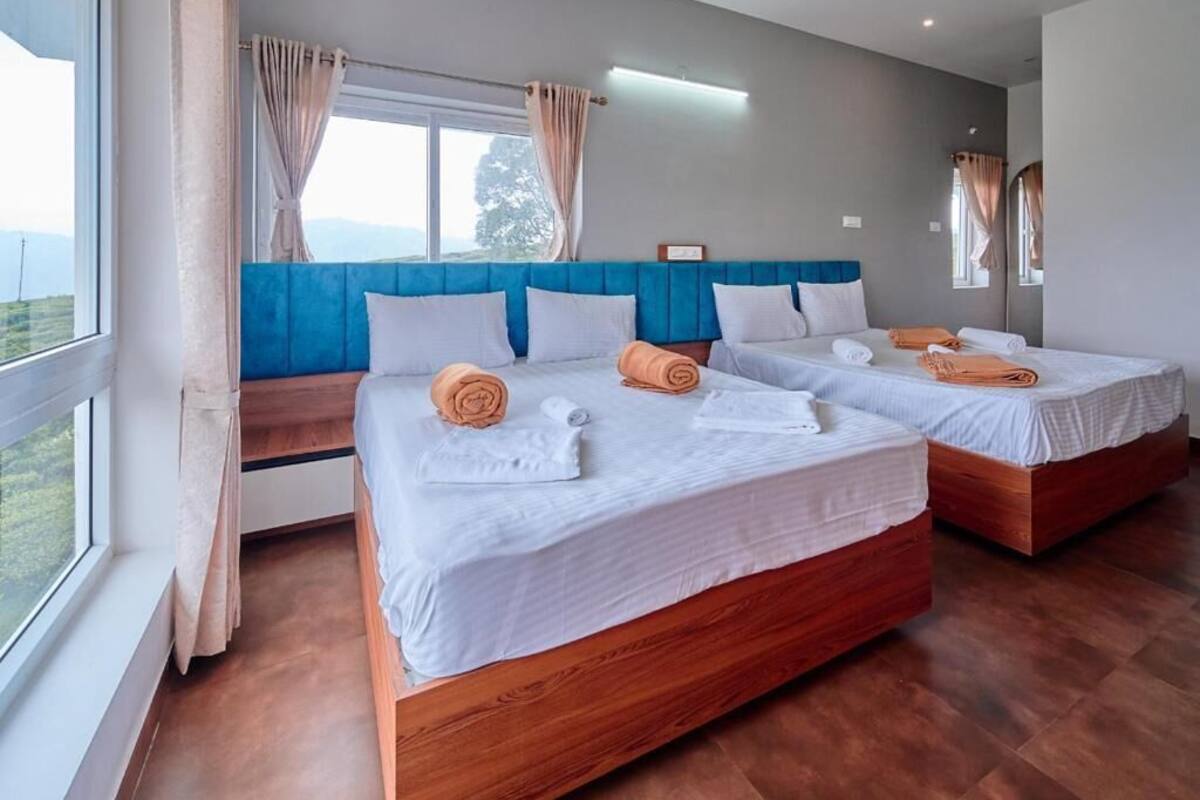 A hotel room with two beds, a large window, and a view of the outdoors.
