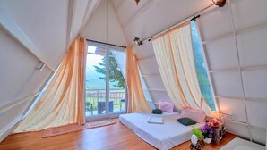 A cozy room with a bed, a small table with a plant, and a window with curtains.