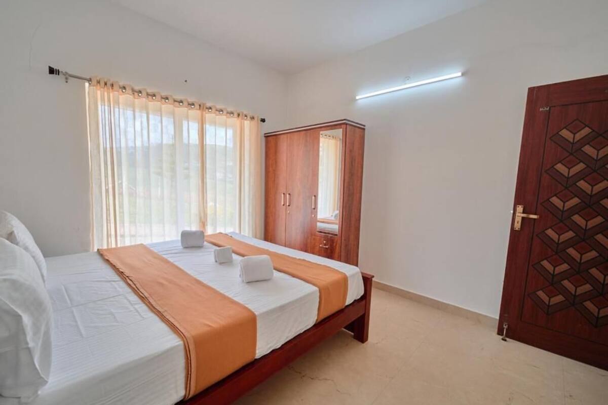 A bedroom with a bed, curtains, a wardrobe, and a door.
