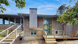 A modern house with a wooden exterior, a chimney, and a front porch. - Drummer Cove Retreat | House in Wellfleet (Wellfleet)