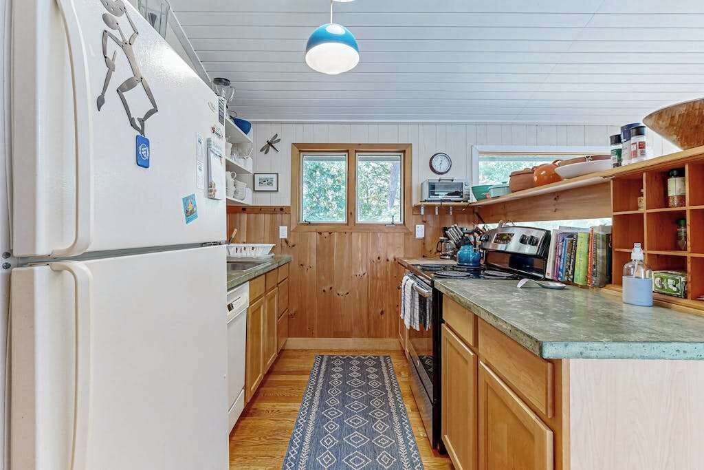 A compact kitchen with wooden cabinets, a refrigerator, a microwave, and a sink.