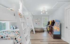 Habitación infantil con literas, juegos de arcade y obras de arte en las paredes.