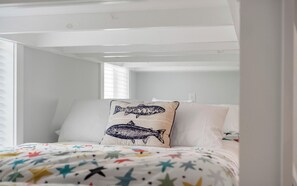 A bedroom with a bunk bed, star-patterned bedding, and two pillows with fish designs. - Resting BeachFace + Private Beach, Bikes & Games (Inlet Beach)