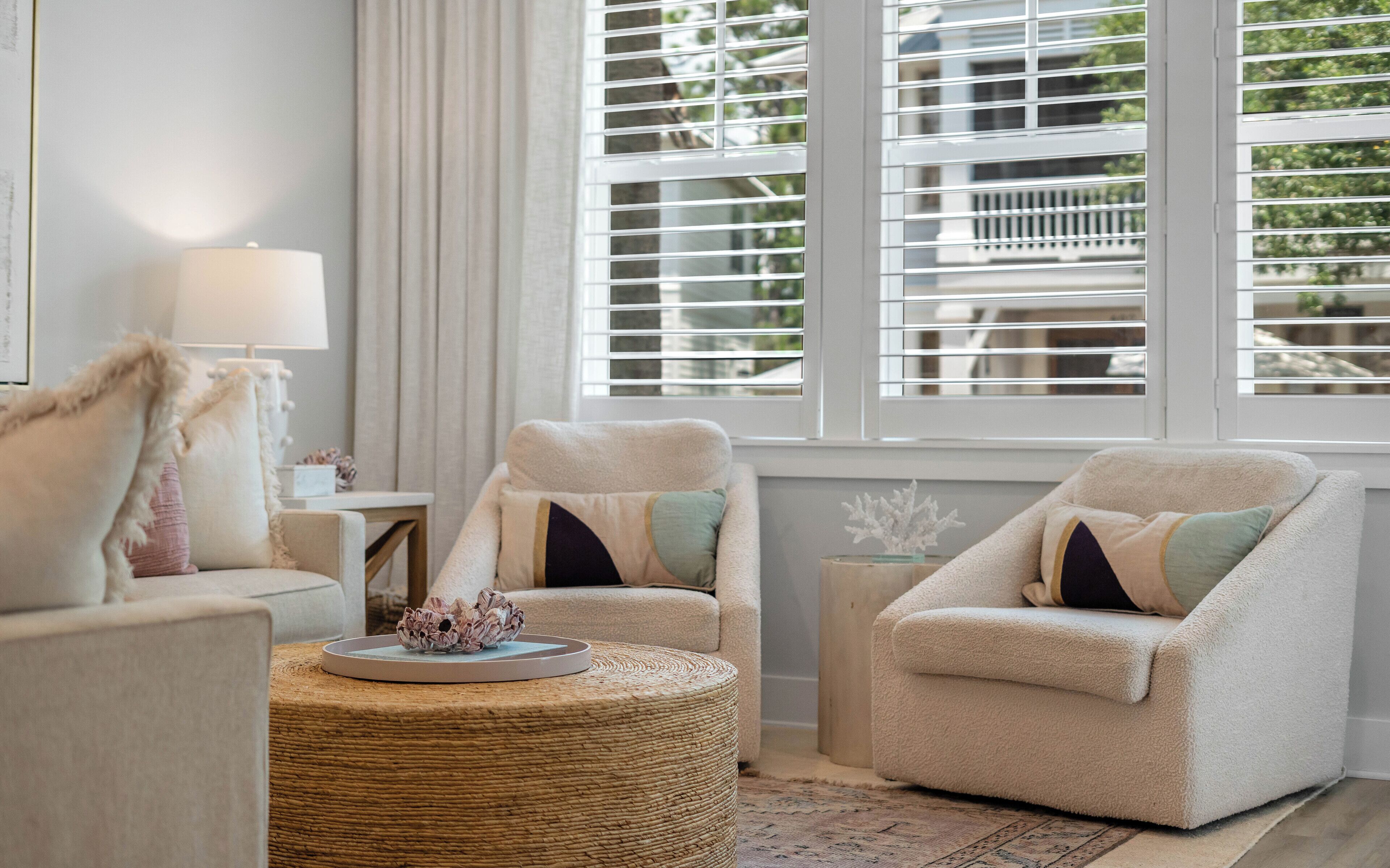A living room with two armchairs, a round coffee table, and a lamp.