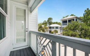 A white building with a balcony, a door with a glass panel, and a clear sky. - Resting BeachFace + Private Beach, Bikes & Games (Inlet Beach)