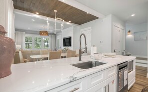 A modern kitchen with a marble countertop, stainless steel sink, and a pendant light. - Resting BeachFace + Private Beach, Bikes & Games (Inlet Beach)