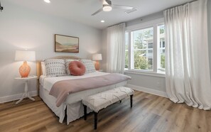 A bedroom with a bed, bedside tables, a ceiling fan, a window with blinds, and a painting on the wall. - Resting BeachFace + Private Beach, Bikes & Games (Inlet Beach)