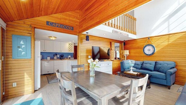 Een houten interieur met een eethoek, een bank en een zichtbare keuken.
