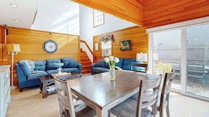 Een ruime woonkamer met houten plafond, een eettafel met stoelen en een zithoek.