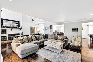 A living room with a sectional sofa, a coffee table, and a patterned rug. - Spacious coastal retreat with heated pool, kayaks, game room & pond views (Centerville)