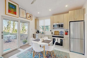 A modern kitchen with a dining area, large windows, and a view of the outdoors. - Stylish seaside escape with harborview rooftop deck, patio & steps to nightlife (Provincetown)