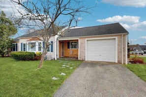 Ein zweigeschossiges Haus mit Garage, Veranda und einem kleinen Garten.
