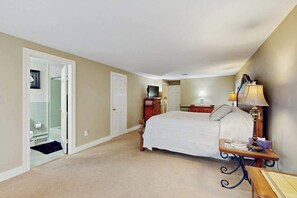Ein Schlafzimmer mit Bett, Nachttisch, Lampe und einer Tür zum Badezimmer.