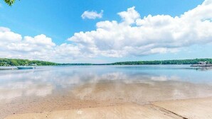 A wide river with boats, clear skies, and distant greenery. - Luxe lakefront home on Follins Pond with private beach, amazing decks & yard (Yarmouth Port)