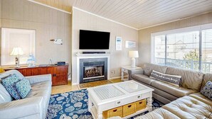 A living room with a fireplace, a television, a sofa, and a coffee table. - Lovely home with private pool, hot tub, foosball, air hockey & easy beach access (Virginia Beach)