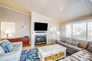 A living room with a fireplace, a television, a sofa, and a coffee table. - Lovely home with private pool, hot tub, foosball, air hockey & easy beach access (Virginia Beach)