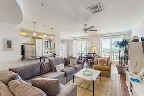 A spacious living area with a sofa, coffee table, and dining table. - Stunning oceanfront condo with panoramic views, balcony, pool, gym & AC (Virginia Beach)