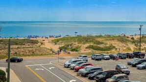 Ein Parkplatz mit Autos, einem Stoppschild und einem Strand im Hintergrund.
