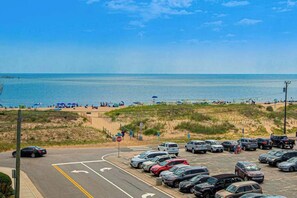 Ein Parkplatz mit Autos, einem Stoppschild und einem Strand im Hintergrund.