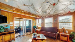 Ein gemütliches Wohnzimmer mit Holzboden, einem braunen Sofa, einem Couchtisch und einem Fernseher.