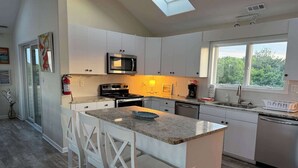 Une cuisine moderne avec des meubles blancs, un plan de travail en granit et un puits de lumière.