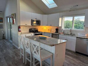 A modern kitchen with white cabinets, a granite countertop, and a skylight. - Sunlit 3-story home with private in-ground pool, balcony, washer/dryer (Virginia Beach)