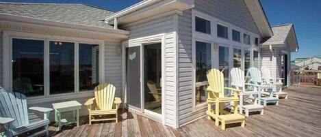 A house with a covered deck, multiple windows, and outdoor seating.