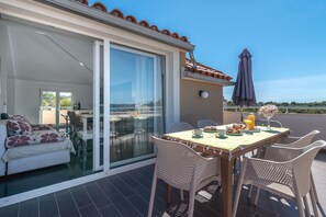 A balcony with a table set for breakfast, wicker chairs, and a view of the sea. - Ivy 2 - apartment with sea view for up to 8 people (Okrug Gornji)