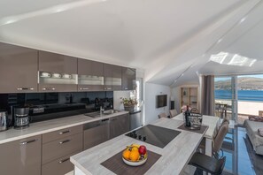 A modern kitchen with a central island, a dining area with a view, and a balcony with a scenic view. - Ivy 2 - apartment with sea view for up to 8 people (Okrug Gornji)