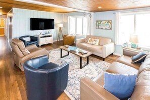 Ein Wohnzimmer mit einer Couch, Sesseln, einem Couchtisch und einem Fernseher.