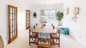 A dining room with a wooden table, chairs, a chandelier, a potted plant, and a small stool. - Tranquil home steps from the water w/private pool, WiFi, private washer/dryer (Virginia Beach)