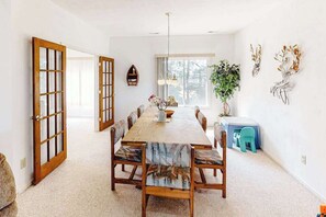 A dining room with a wooden table, chairs, a chandelier, a potted plant, and a small stool. - Tranquil home steps from the water w/private pool, WiFi, private washer/dryer (Virginia Beach)