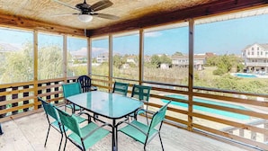 A covered patio with a table and chairs, large windows, and a view of a swimming pool and houses. - Tranquil home steps from the water w/private pool, WiFi, private washer/dryer (Virginia Beach)