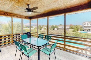 A covered patio with a table and chairs, large windows, and a view of a swimming pool and houses. - Tranquil home steps from the water w/private pool, WiFi, private washer/dryer (Virginia Beach)