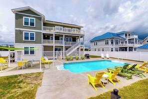 A two-story building with a swimming pool, outdoor seating, and a fenced area. - Oceanfront home with elevator, pool, game room, private washer/dryer, & WiFi (Virginia Beach)
