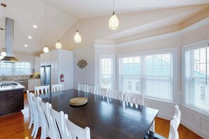 A spacious kitchen with a large island, white chairs, and pendant lighting. - Oceanfront home with elevator, pool, game room, private washer/dryer, & WiFi (Virginia Beach)