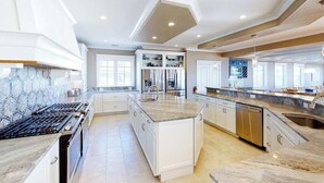 A spacious kitchen with a central island, built-in appliances, and a large window providing natural light. - Wonderful beachfront home w/private indoor & outdoor pools, WiFi, AC, deck (Virginia Beach)