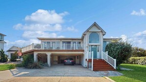 A two-story house with a garage, a balcony, and a staircase leading to the second floor. - 8 BDR & 7.5 BA Luxury Beach House w/private pool & hot tub (Virginia Beach)