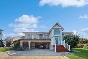 A two-story house with a garage, a balcony, and a staircase leading to the second floor. - 8 BDR & 7.5 BA Luxury Beach House w/private pool & hot tub (Virginia Beach)