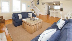 A living room with a sofa, a coffee table, and a staircase leading to a kitchen.